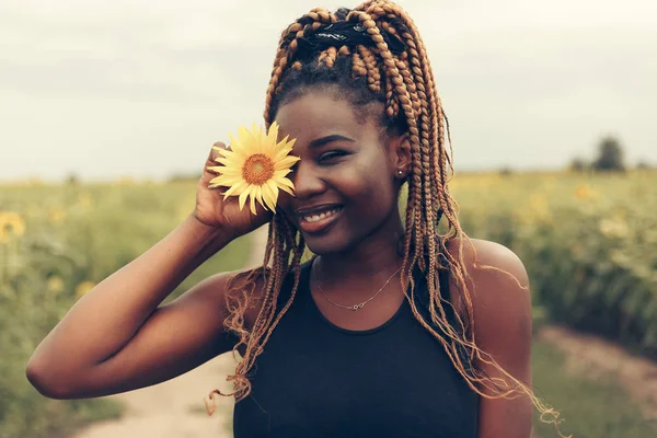 Afro-Américaine dans un champ de fleurs jaunes au coucher du soleil — Photo