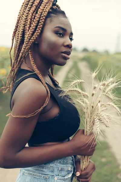 Афроамериканка в поле желтых цветов на закате — стоковое фото