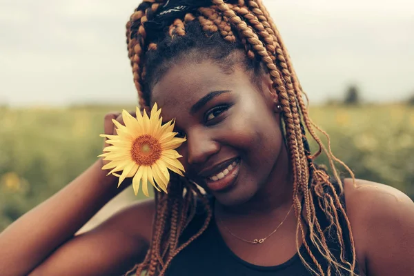 Menina afro-americana em um campo de flores amarelas ao pôr do sol — Fotografia de Stock