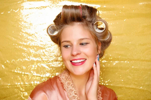 Menina bonita em encrespadores de cabelo isolado em ouro — Fotografia de Stock