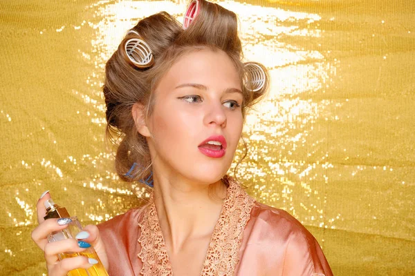 Hermosa chica en rizadores de pelo aislado en oro — Foto de Stock