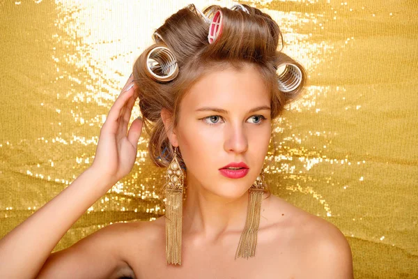 Beautiful girl in hair curlers isolated on gold — Stock Photo, Image