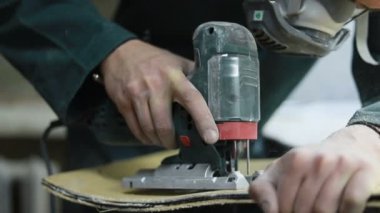 Meslek, insanlar, marangozluk, duygu ve insanlar kavramı-bir marangoz bir elektrikli jigsaw ile bir tahta keser. pateboardlar imalatı. Koruyucu Giyim ve maske vardır. 4k