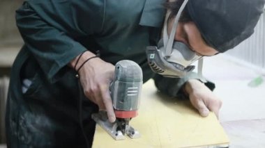 Meslek, insanlar, marangozluk, duygu ve insanlar kavramı-bir marangoz bir elektrikli jigsaw ile bir tahta keser. pateboardlar imalatı. Koruyucu Giyim ve maske vardır. 4k