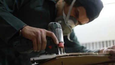 Meslek, insanlar, marangozluk, duygu ve insanlar kavramı-bir marangoz bir elektrikli jigsaw ile bir tahta keser. pateboardlar imalatı. Koruyucu Giyim ve maske vardır. 4k