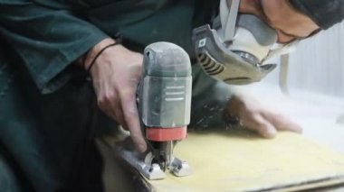 Meslek, insanlar, marangozluk, duygu ve insanlar kavramı-bir marangoz bir elektrikli jigsaw ile bir tahta keser. pateboardlar imalatı. Koruyucu Giyim ve maske vardır. 4k