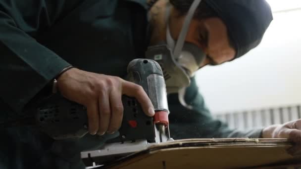 情感和人的概念 木匠削减板与电动拼图 滑板的制造 他有防护服和面罩4K — 图库视频影像