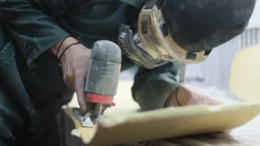 Meslek, insanlar, marangozluk, duygu ve insanlar kavramı-bir marangoz bir elektrikli jigsaw ile bir tahta keser. pateboardlar imalatı. Koruyucu Giyim ve maske vardır. 4k
