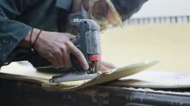 Meslek, insanlar, marangozluk, duygu ve insanlar kavramı-bir marangoz bir elektrikli jigsaw ile bir tahta keser. pateboardlar imalatı. Koruyucu Giyim ve maske vardır. 4k