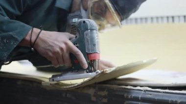 Meslek, insanlar, marangozluk, duygu ve insanlar kavramı-bir marangoz bir elektrikli jigsaw ile bir tahta keser. pateboardlar imalatı. Koruyucu Giyim ve maske vardır. 4k