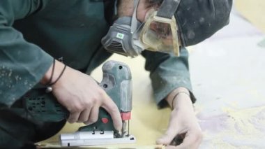 Meslek, insanlar, marangozluk, duygu ve insanlar kavramı-bir marangoz bir elektrikli jigsaw ile bir tahta keser. pateboardlar imalatı. Koruyucu Giyim ve maske vardır. 4k