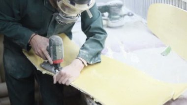 Meslek, insanlar, marangozluk, duygu ve insanlar kavramı-bir marangoz bir elektrikli jigsaw ile bir tahta keser. pateboardlar imalatı. Koruyucu Giyim ve maske vardır. 4k
