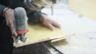 Meslek, insanlar, marangozluk, duygu ve insanlar kavramı-bir marangoz bir elektrikli jigsaw ile bir tahta keser. pateboardlar imalatı. Koruyucu Giyim ve maske vardır. 4k