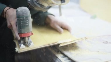 Meslek, insanlar, marangozluk, duygu ve insanlar kavramı-bir marangoz bir elektrikli jigsaw ile bir tahta keser. pateboardlar imalatı. Koruyucu Giyim ve maske vardır. 4k