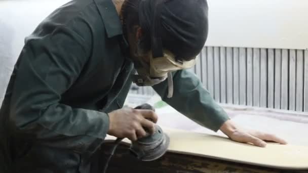 人の大工 コンセプト 若い職人男 Sandering デッキ Sandering ツールを使って移します スケート ボードの製造 彼は防護服とマスク — ストック動画