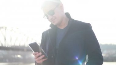 Genç yakışıklı işadamı cadde boyunca geri telefon yürüyüş İş görüşmesinde şık erkek takım elbise görünümüdür konuşuyor, cityscape arka plan üzerinde duruyor. Konsept: teknoloji, iş.