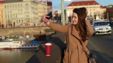 Bir kadın selfies bir şehirde yapma bir kağıt kahve Kupası ile önden görünümü. Sosyal medya kavramı. Gerçek zamanlı orta atış kilitli