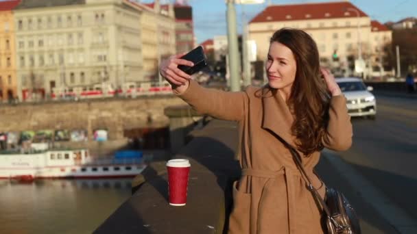 都市に Selfies を作る紙のコーヒー カップを持つ女性の正面 ソーシャル メディアの概念 リアルタイム ミディアム ショット ダウン — ストック動画