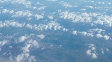 Mavi gökyüzü ile uçak penceresinden bulutların üzerinde hava görünümünü çarpıcı görüntüleri. Dünya'dan gökyüzüne Bulutların arasından bir bakış. 4k video. Havadan görüntüleri. Seyahat kavramı