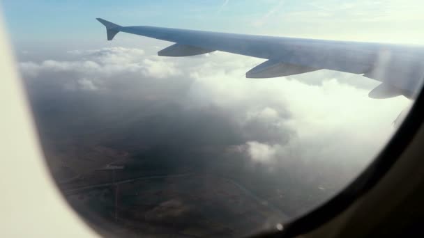从蓝天的飞机窗口 在云层上方看到鸟图的令人惊叹的画面 从天空中通过云层看到了地球 空中镜头 旅游理念 — 图库视频影像