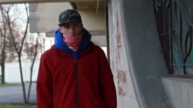 Kar maskeli, kimliği belirsiz genç adam duvarın yanında duruyor ve elinde sprey boya tutuyor. Vandalizm, sokak sanatı, hobi. Banliyö bölgesi, eğlence, isyan, protesto. Görüntüyü kapat