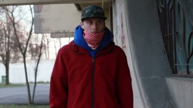 Kar maskeli, kimliği belirsiz genç adam duvarın yanında duruyor ve elinde sprey boya tutuyor. Vandalizm, sokak sanatı, hobi. Banliyö bölgesi, eğlence, isyan, protesto. Görüntüyü kapat