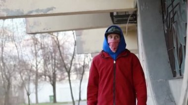 Kar maskeli, kimliği belirsiz genç adam duvarın yanında duruyor ve elinde sprey boya tutuyor. Vandalizm, sokak sanatı, hobi. Banliyö bölgesi, eğlence, isyan, protesto. Görüntüyü kapat