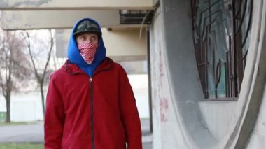 Kar maskeli, kimliği belirsiz genç adam duvarın yanında duruyor ve elinde sprey boya tutuyor. Vandalizm, sokak sanatı, hobi. Banliyö bölgesi, eğlence, isyan, protesto. Görüntüyü kapat