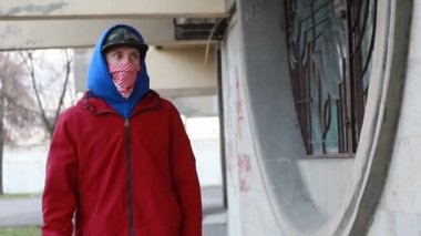 Kar maskeli, kimliği belirsiz genç adam duvarın yanında duruyor ve elinde sprey boya tutuyor. Vandalizm, sokak sanatı, hobi. Banliyö bölgesi, eğlence, isyan, protesto. Görüntüyü kapat