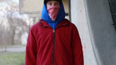 Kar maskeli, kimliği belirsiz genç adam duvarın yanında duruyor ve elinde sprey boya tutuyor. Vandalizm, sokak sanatı, hobi. Banliyö bölgesi, eğlence, isyan, protesto. Görüntüyü kapat