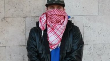 Kar maskeli, kimliği belirsiz genç adam duvarın yanında duruyor ve elinde sprey boya tutuyor. Vandalizm, sokak sanatı, hobi. Banliyö bölgesi, eğlence, isyan, protesto. Görüntüyü kapat