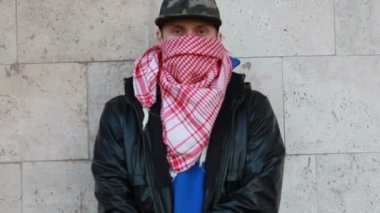 Kar maskeli, kimliği belirsiz genç adam duvarın yanında duruyor ve elinde sprey boya tutuyor. Vandalizm, sokak sanatı, hobi. Banliyö bölgesi, eğlence, isyan, protesto. Görüntüyü kapat