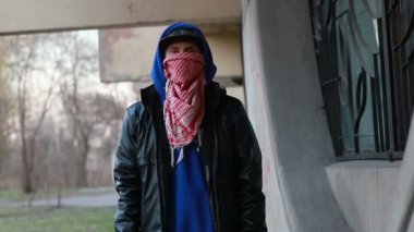 Kar maskeli, kimliği belirsiz genç adam duvarın yanında duruyor ve elinde sprey boya tutuyor. Vandalizm, sokak sanatı, hobi. Banliyö bölgesi, eğlence, isyan, protesto. Görüntüyü kapat