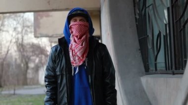 Kar maskeli, kimliği belirsiz genç adam duvarın yanında duruyor ve elinde sprey boya tutuyor. Vandalizm, sokak sanatı, hobi. Banliyö bölgesi, eğlence, isyan, protesto. Görüntüyü kapat