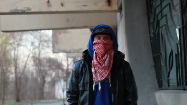 Kar maskeli, kimliği belirsiz genç adam duvarın yanında duruyor ve elinde sprey boya tutuyor. Vandalizm, sokak sanatı, hobi. Banliyö bölgesi, eğlence, isyan, protesto. Görüntüyü kapat
