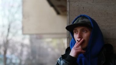 Portrait of stylish man smoking cigarette on urban background during sunset, slow motion, close up