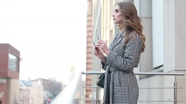 有吸引力的女孩穿着外套在城市的大街上 阳光灿烂 比转向相机和微笑 慢动作 美丽的 — 图库视频影像