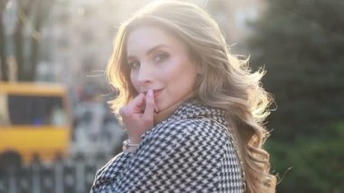 Bir şehirde sokakta bir ceket çekici kız, güneş parlıyor, kamera ve gülümsüyor döner daha. portre mutlu yavaş hareket yaz yüz günbatımı güzel bayan açık closeup sevimli