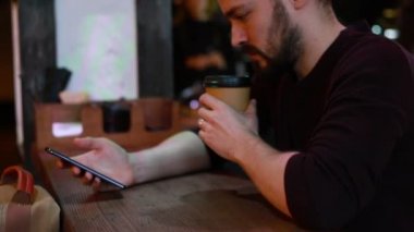 Akıllı telefonu kullanan ve kafede kameraya gülümseyen adam. Mutlu yakışıklı genç adam cep telefonu tutan ve açık kafede otururken kameraya bakıyor. Duygu kavramı