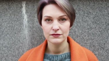 Portre genç çekici gülümseme kadın şehir merkezinde kamera bakmak mutlu moda kız yaz yüz teknoloji güneş güzel yavaş hareket sokak hissediyorum. şehirde turuncu bir ceket bir kız portresi