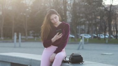 Güneşli şehir sokakları yürüyüş ve sohbet arkadaş, neşeli hippi kız açık havada cep telefonu kullanarak, gün batımı arka plan ile çekici genç kadın