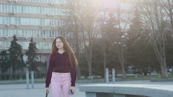 迷人的年轻女子漫步在阳光明媚的城市街道和朋友聊天 快乐的时髦女孩使用手机户外 日落背景 — 图库视频影像