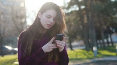 Güneşli şehir sokakları yürüyüş ve sohbet arkadaş, neşeli hippi kız açık havada cep telefonu kullanarak, gün batımı arka plan ile çekici genç kadın
