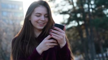 Güneşli şehir sokakları yürüyüş ve sohbet arkadaş, neşeli hippi kız açık havada cep telefonu kullanarak, gün batımı arka plan ile çekici genç kadın