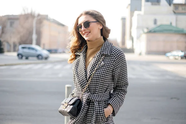 Привлекательная девушка в пальто на улице в городе, светит солнце — стоковое фото