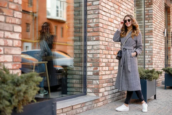 Menina atraente em um casaco na rua em uma cidade, o sol está brilhando — Fotografia de Stock