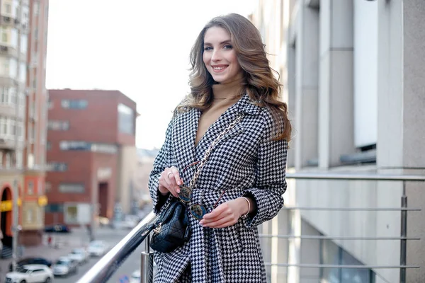 Привлекательная девушка в пальто на улице в городе, светит солнце — стоковое фото