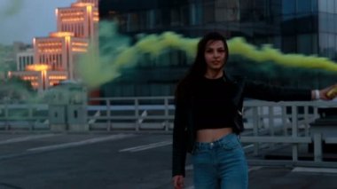 Kadın acil durum işaret sinyali veriyor. Sis bombası olan hipster kız. Çatı otoparkında gün batımında sis bombası ile dışarıda genç kadın