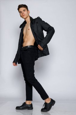 Siyah ceketli ve kot pantolonlu genç kaslı adam. Genç yakışıklı, deri ceketli, çıplak gövde, duygusal poz, beyaz arka plan, modern adam, yaşam tarzı insan konsepti.