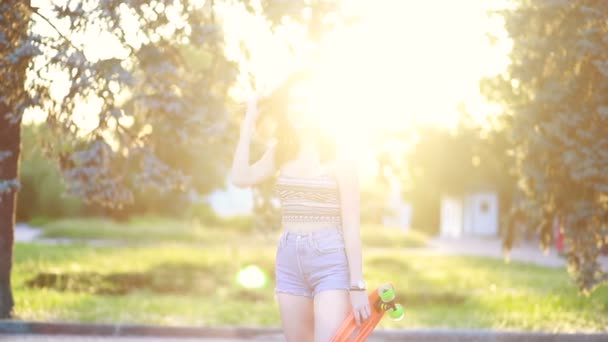 生活方式 极端和人的概念 美丽的女孩在城市的道路上 在阳光灿烂的天气 日落时分 一个穿着长板衣服的时髦女郎面带微笑 慢动作 — 图库视频影像